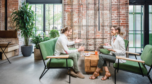 Two people take advantage of collaborative office space planning with a casual, impromptu meeting in a modern office.