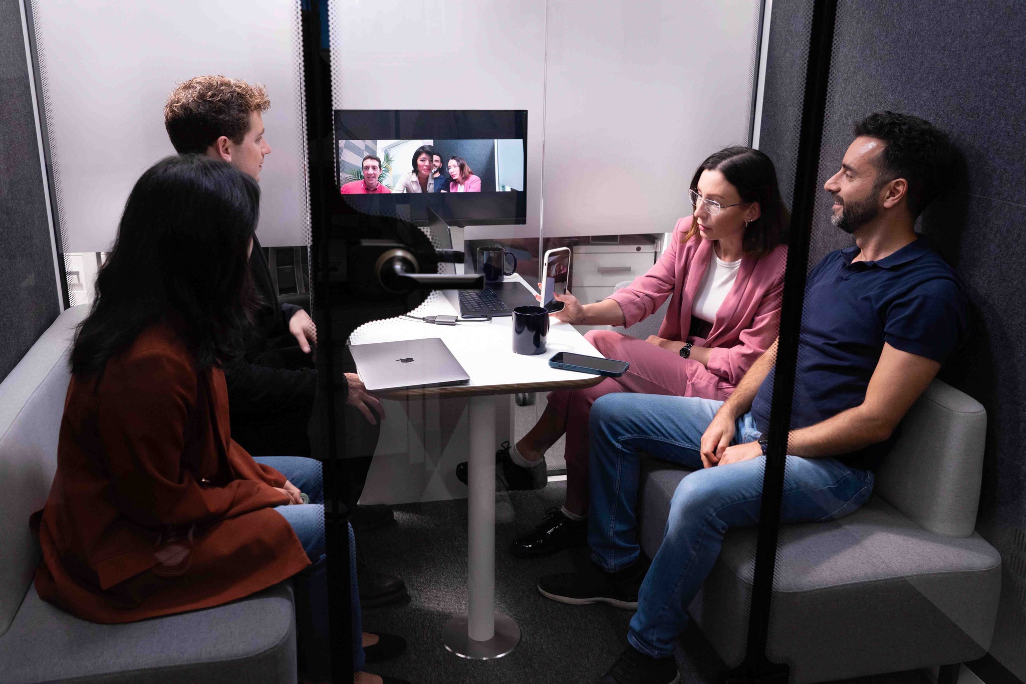 A team of four employees takes a video meeting inside a Thinktanks office pod, demonstrating an effective meeting environment.