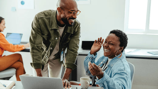 A man and woman laugh as they work together on a laptop, illustrating the collaborative nature of flexible workspaces. 