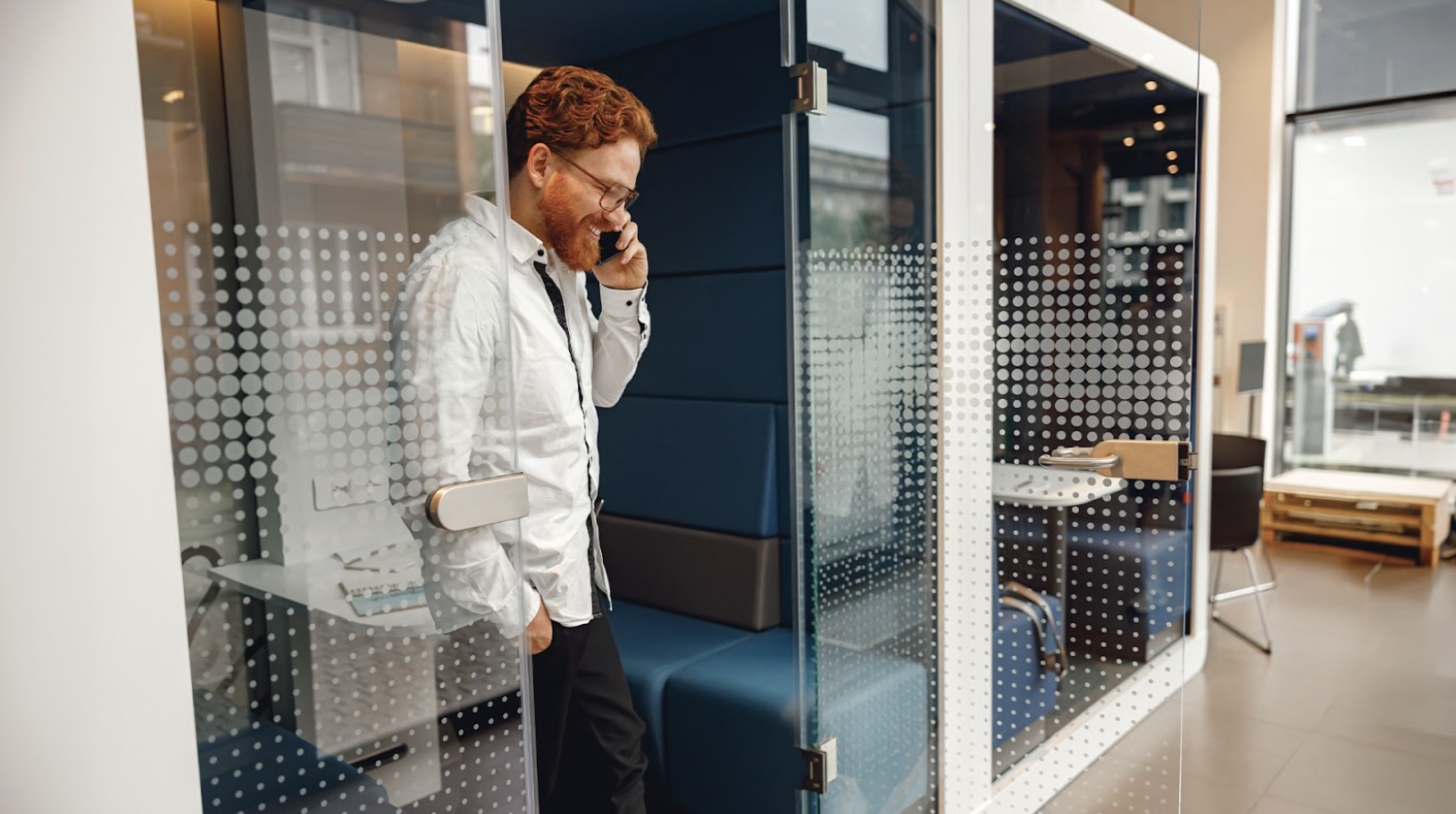 A man talks on the phone inside a private office pod, showcasing the benefits of a modern modular office design.