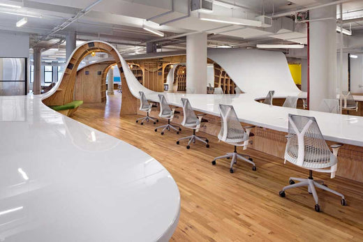  An open layout office space with sleek, curved workstations and minimalist design, showcasing modern office design trends.