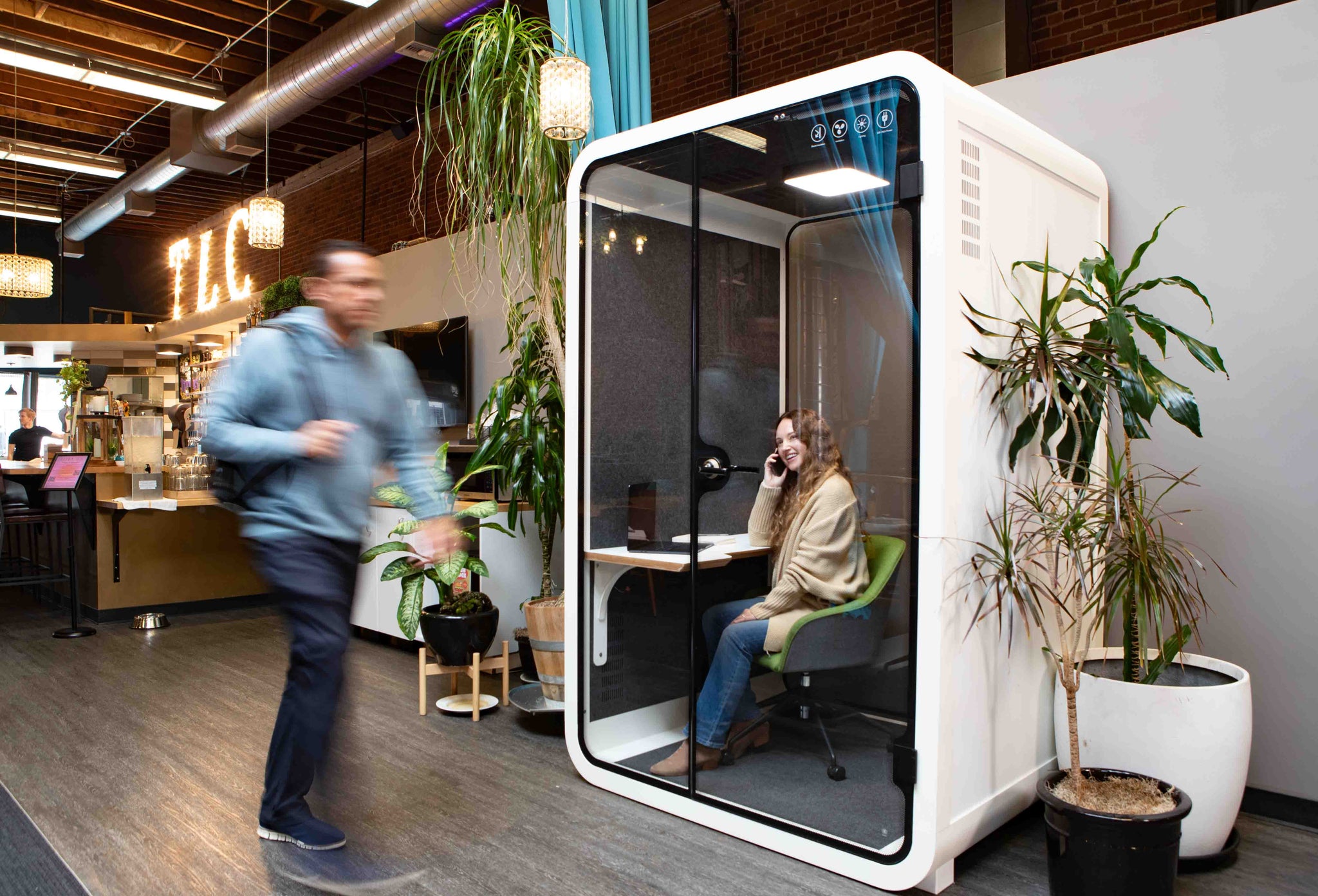 A woman seated inside a Zoom Room takes a phone call at the San Francisco Thinktanks showroom. 